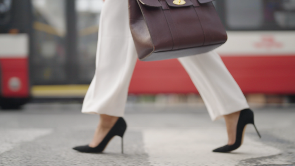 Graduate from Ivey Business School MBA program walking down a Toronto street as the street car passes behind her.